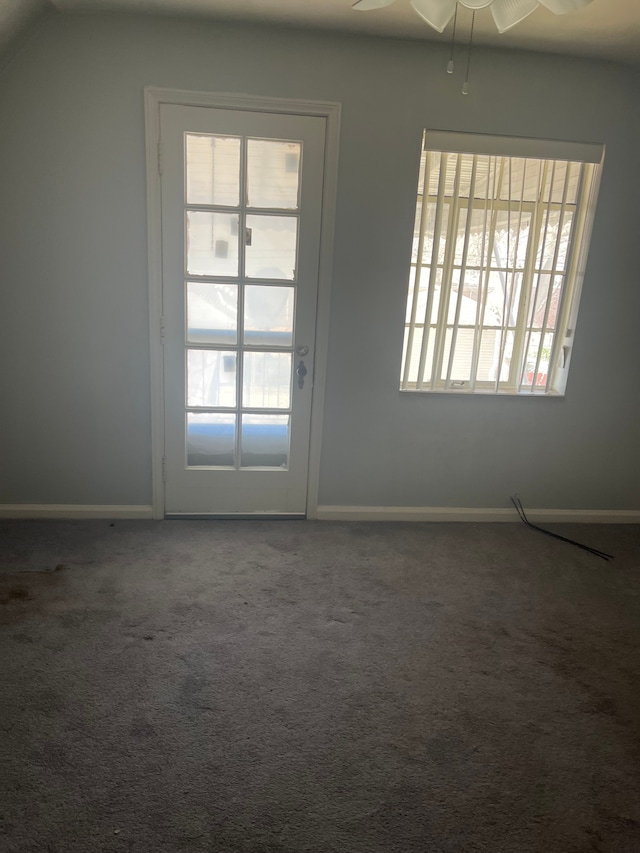 unfurnished room featuring lofted ceiling, baseboards, dark carpet, and ceiling fan