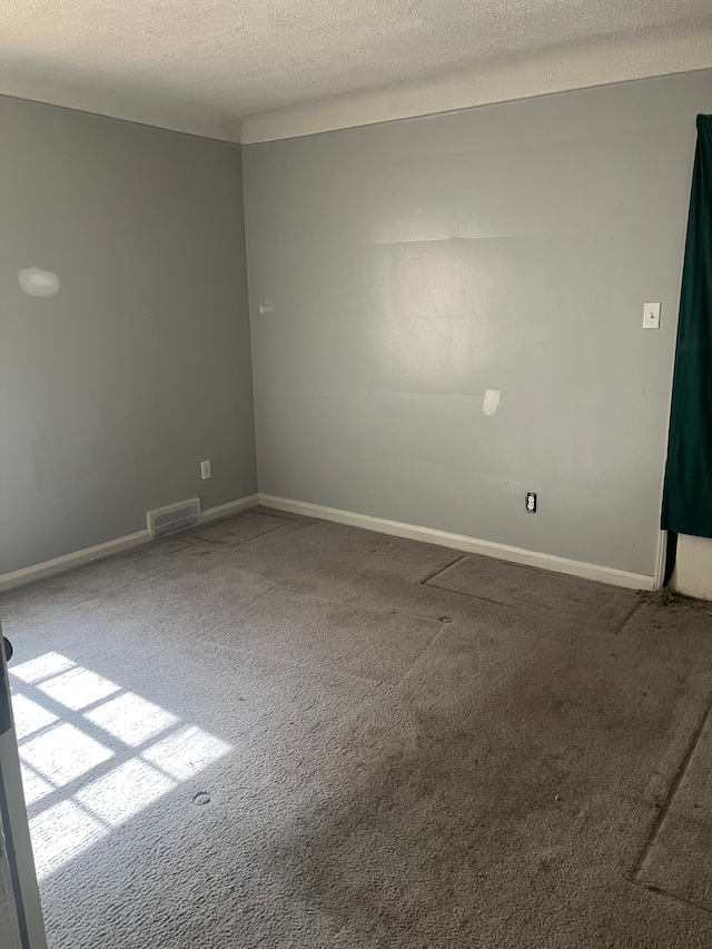 carpeted spare room featuring baseboards, visible vents, and a textured ceiling