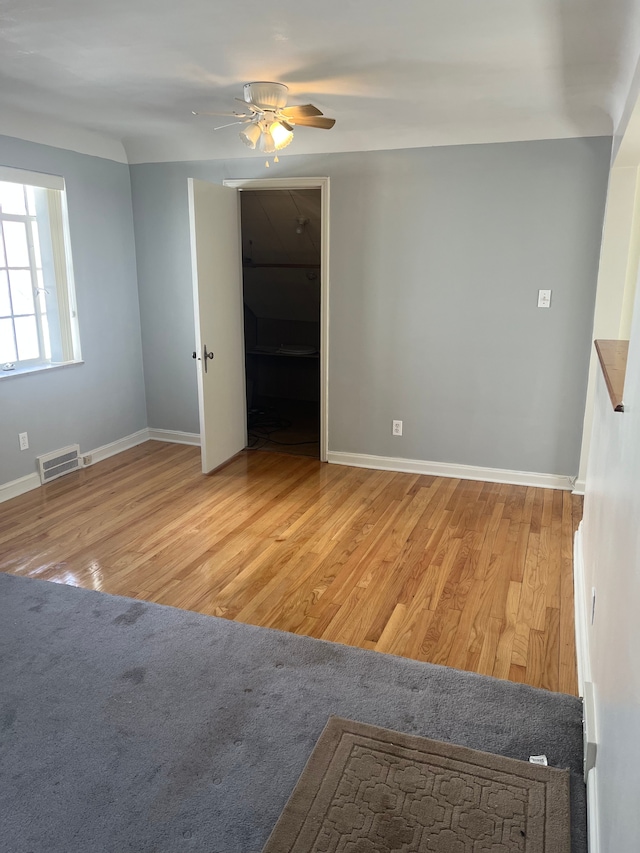 spare room featuring baseboards, wood finished floors, visible vents, and ceiling fan