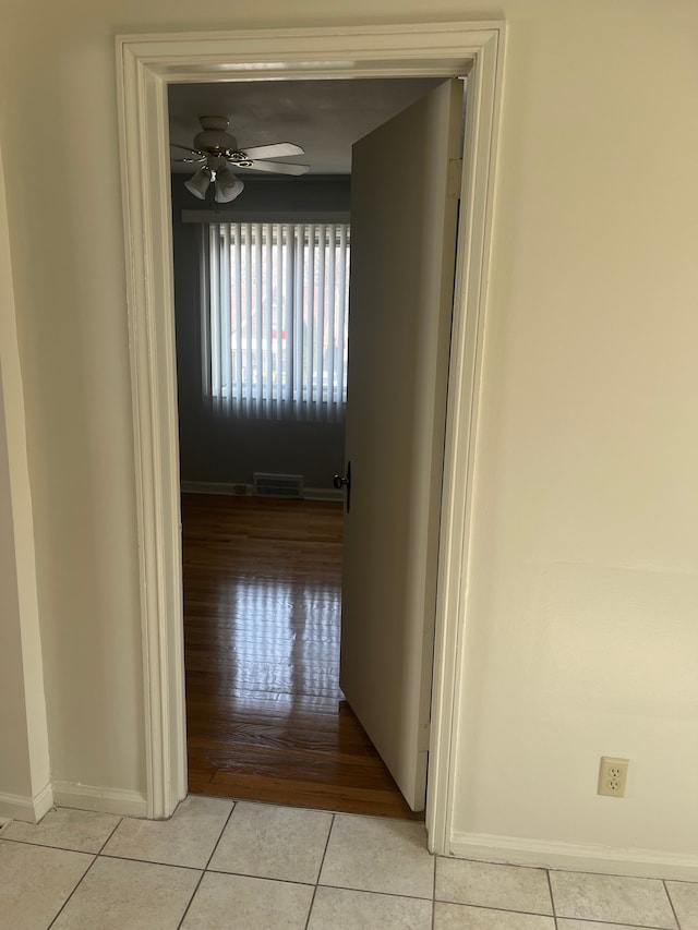 hallway with light tile patterned floors, visible vents, and baseboards