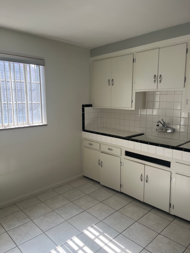 kitchen featuring tile countertops, tasteful backsplash, and white cabinets