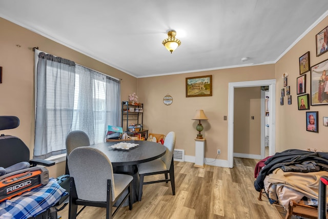 dining room with visible vents, baseboards, light wood-type flooring, and ornamental molding