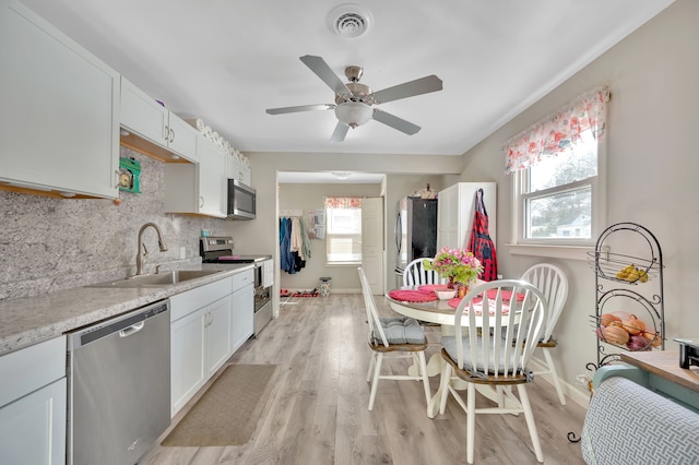 kitchen with tasteful backsplash, ceiling fan, light wood-style floors, stainless steel appliances, and a sink