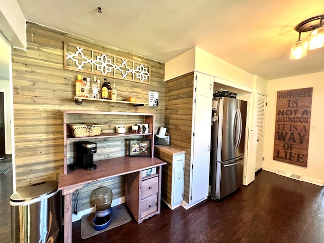 kitchen with visible vents, dark wood finished floors, freestanding refrigerator, white cabinets, and wood walls