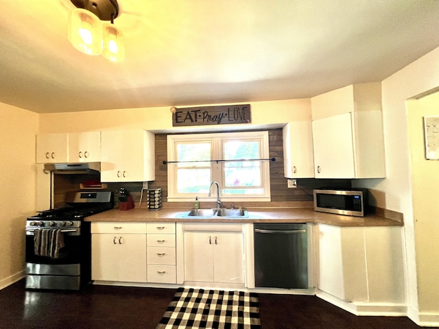 kitchen featuring a sink, under cabinet range hood, stainless steel appliances, white cabinets, and baseboards