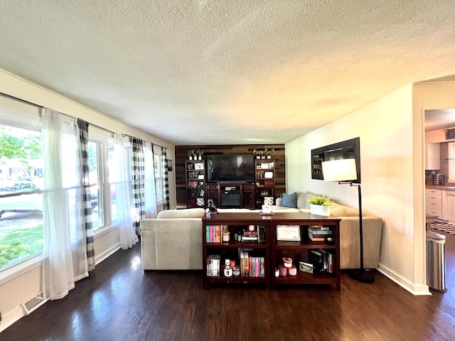 living room with visible vents, a textured ceiling, and wood finished floors