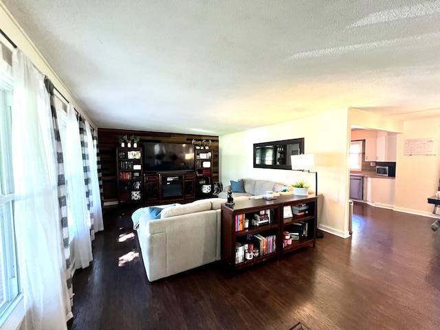 living area with baseboards, a textured ceiling, and wood finished floors