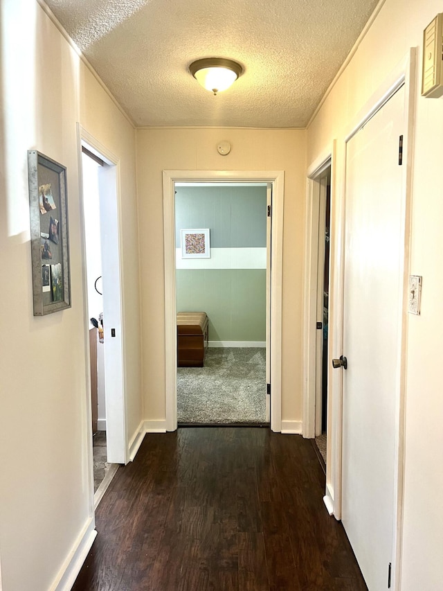 hall featuring baseboards, a textured ceiling, and dark wood-style floors