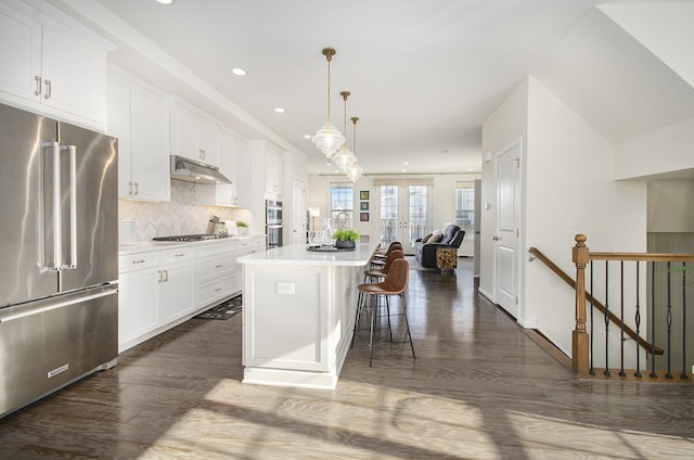 2822 Purley Ave, Ann Arbor, MI 48105 - kitchen featuring white cabinets, under cabinet range hood, recessed lighting, stainless steel appliances, and a breakfast bar area