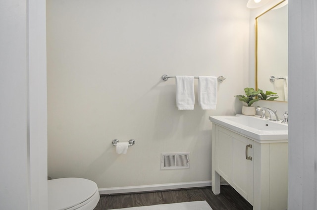 2822 Purley Ave, Ann Arbor, MI 48105 - half bathroom with vanity, baseboards, toilet, visible vents, and wood finished floors