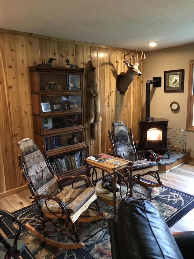 living area featuring a wood stove, wood finished floors, and wood walls