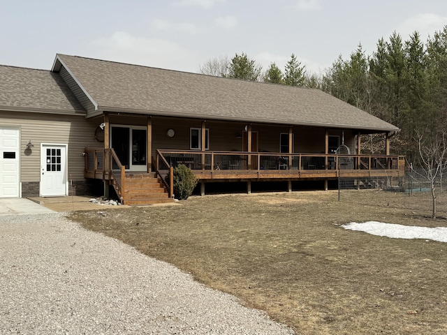 view of front of house featuring driveway, roof with shingles, an attached garage, covered porch, and stone siding