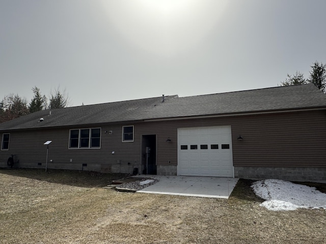 back of house with a garage, roof with shingles, and concrete driveway