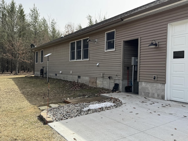 rear view of house featuring crawl space and a garage