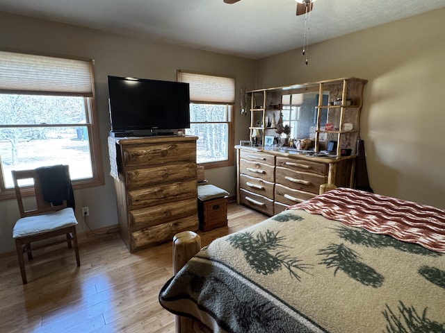 bedroom featuring baseboards, multiple windows, and light wood-style flooring