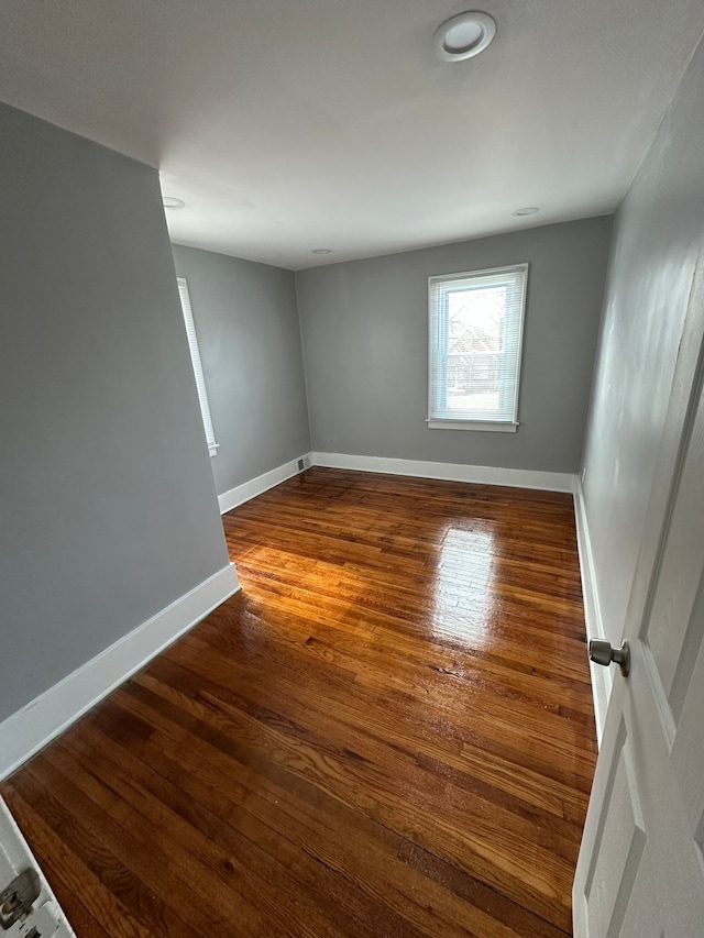 unfurnished room with baseboards and wood-type flooring