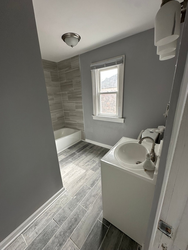 full bathroom with shower / tub combination, baseboards, vanity, and wood finish floors