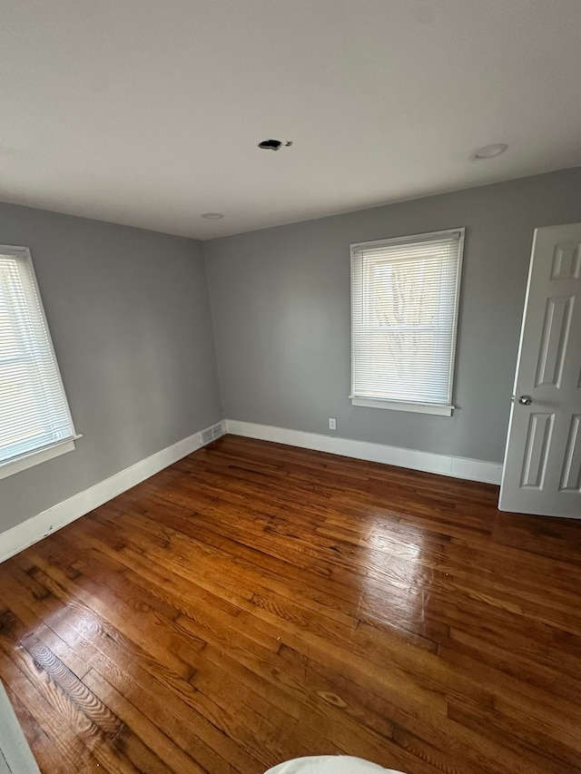 spare room with a wealth of natural light, visible vents, baseboards, and hardwood / wood-style floors