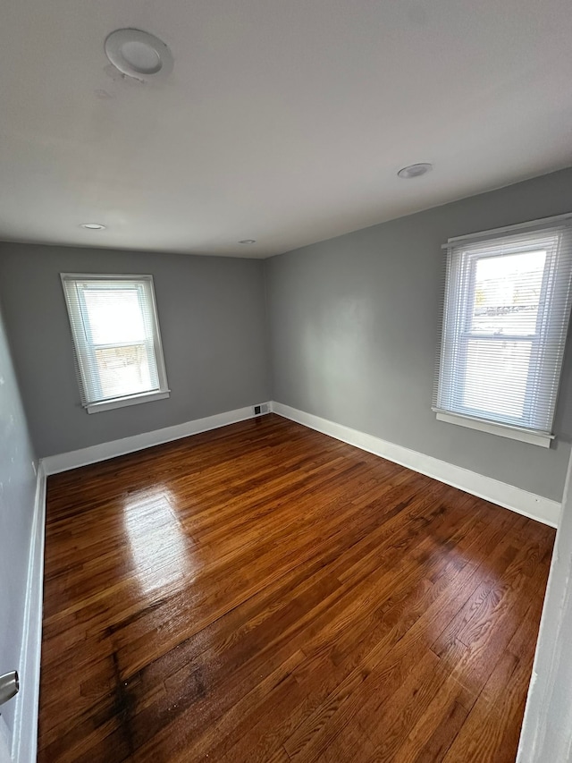 spare room with dark wood finished floors, visible vents, and baseboards