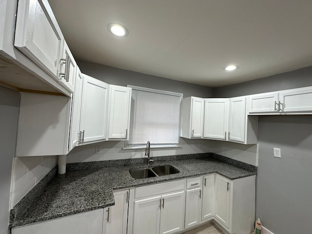 kitchen featuring a sink, dark stone counters, and white cabinets