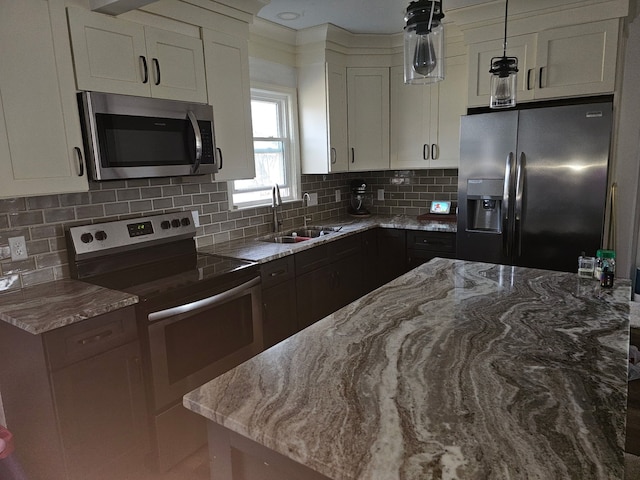 kitchen featuring backsplash, light stone counters, appliances with stainless steel finishes, white cabinets, and a sink