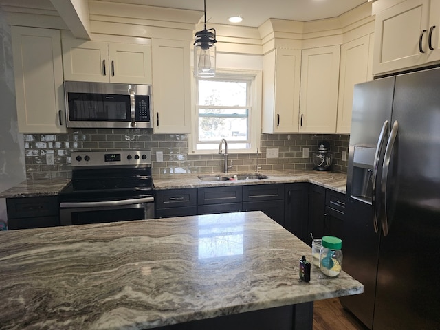 kitchen with white cabinetry, appliances with stainless steel finishes, light stone countertops, and a sink