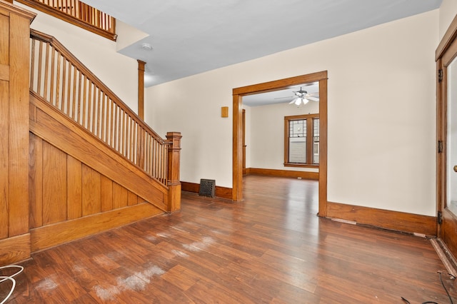 unfurnished living room with baseboards, stairs, ceiling fan, and wood finished floors