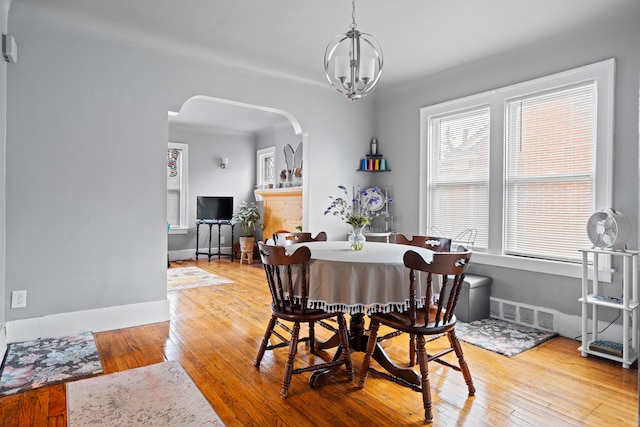 dining room with arched walkways, visible vents, light wood finished floors, and an inviting chandelier