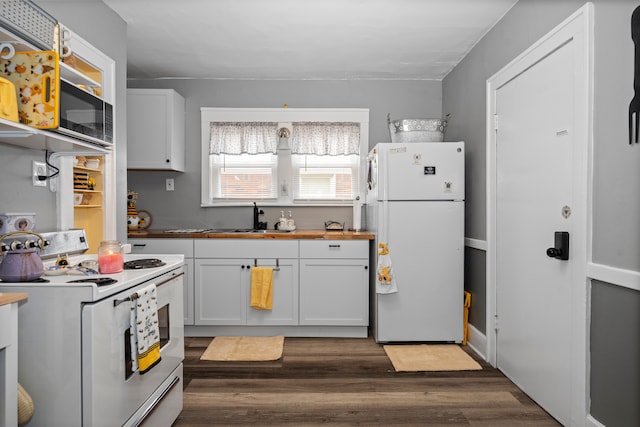 kitchen featuring dark wood finished floors, butcher block countertops, white cabinets, white appliances, and a sink