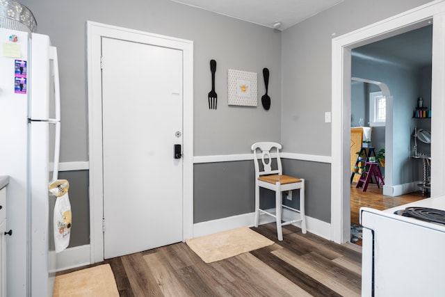 interior space with wood finished floors, arched walkways, and baseboards