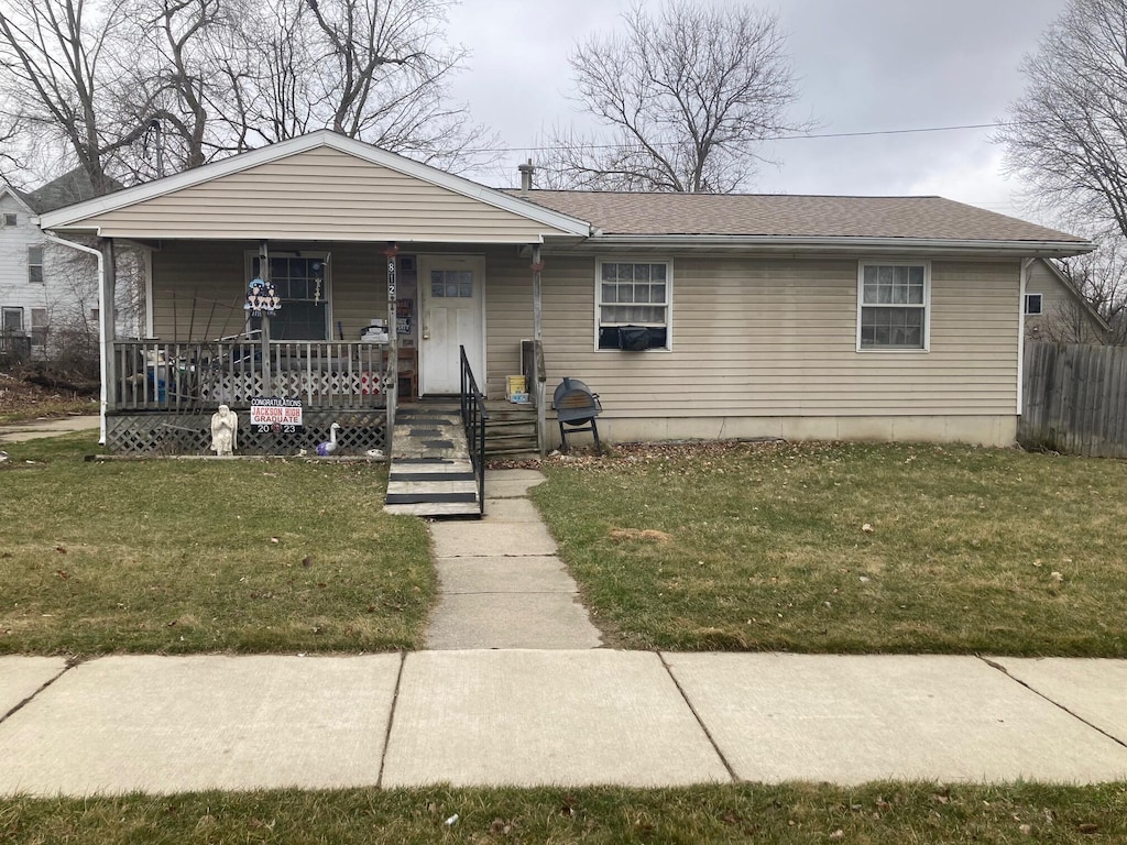 bungalow-style home featuring a front lawn, fence, and covered porch