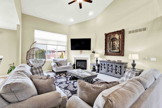 carpeted living area featuring visible vents, baseboards, ceiling fan, and a glass covered fireplace