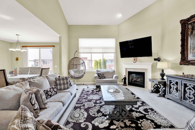 living room featuring a glass covered fireplace, carpet flooring, a healthy amount of sunlight, and a chandelier