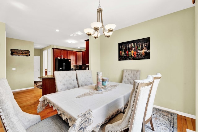 dining room with an inviting chandelier, recessed lighting, baseboards, and light wood-type flooring