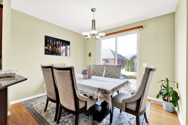 dining room featuring a chandelier, visible vents, baseboards, and hardwood / wood-style flooring