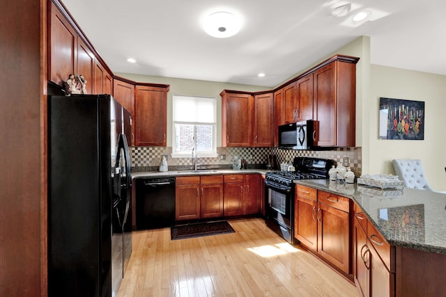 kitchen with black appliances, a peninsula, tasteful backsplash, and a sink