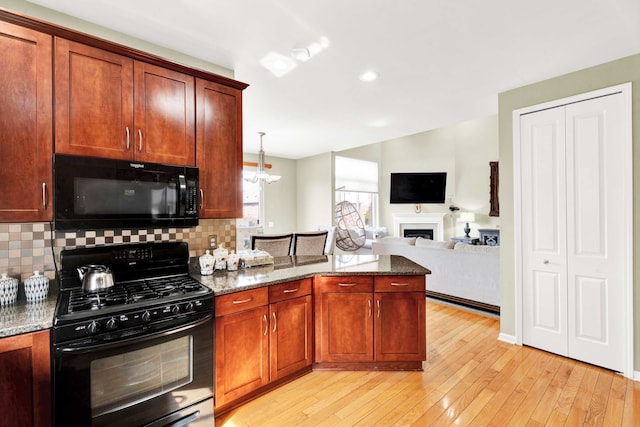 kitchen with stone counters, light wood-type flooring, black appliances, and a peninsula