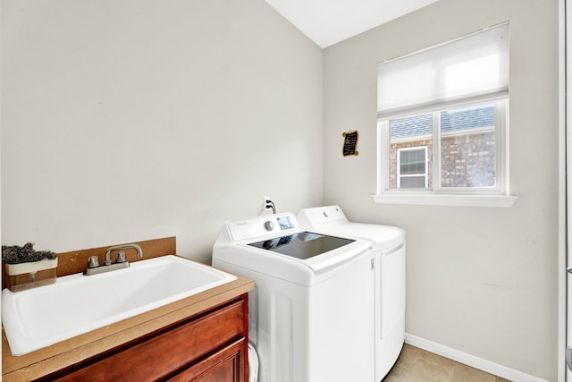 clothes washing area with baseboards, light tile patterned floors, washer and dryer, cabinet space, and a sink