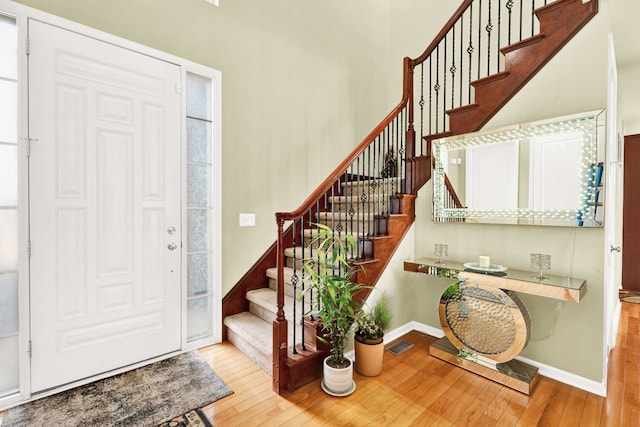 foyer entrance featuring visible vents, stairs, baseboards, and wood-type flooring