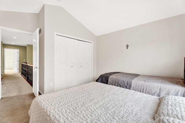 bedroom with a closet, visible vents, carpet, and vaulted ceiling