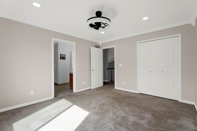 unfurnished bedroom with crown molding, carpet, baseboards, and a closet