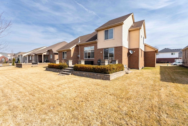 back of house with a yard, brick siding, and a residential view