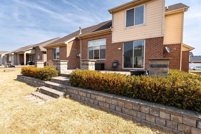 rear view of property featuring brick siding and a shingled roof