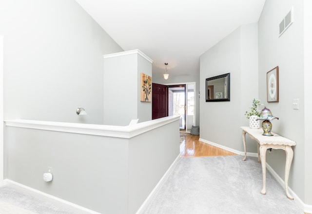 hall featuring visible vents, an upstairs landing, lofted ceiling, and baseboards