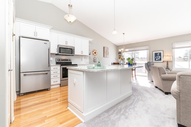 kitchen featuring open floor plan, stainless steel appliances, light wood-style floors, an inviting chandelier, and white cabinetry