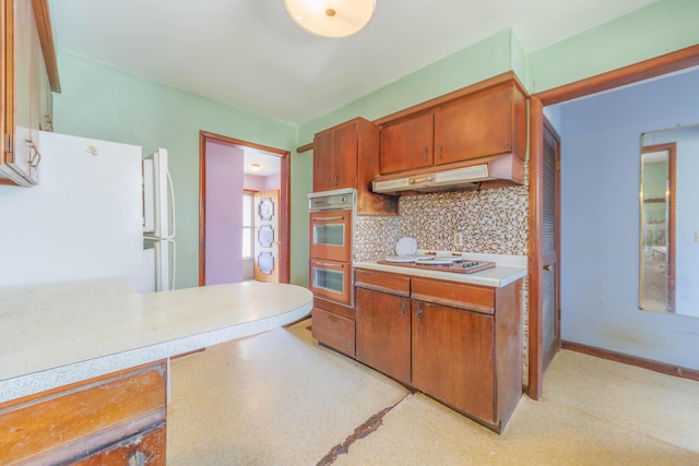 kitchen with stovetop, freestanding refrigerator, light countertops, under cabinet range hood, and tasteful backsplash