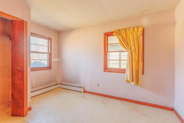 carpeted spare room with a baseboard radiator and baseboards