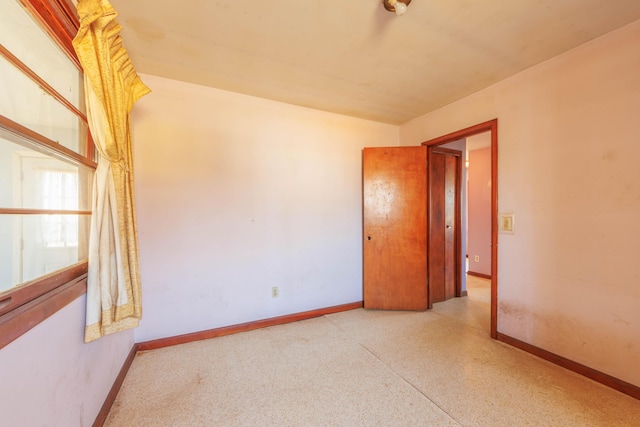 unfurnished room with speckled floor and baseboards