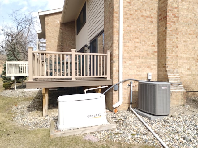 view of side of property with a wooden deck, brick siding, and central AC