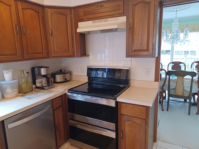 kitchen with under cabinet range hood, light countertops, brown cabinets, a notable chandelier, and stainless steel appliances